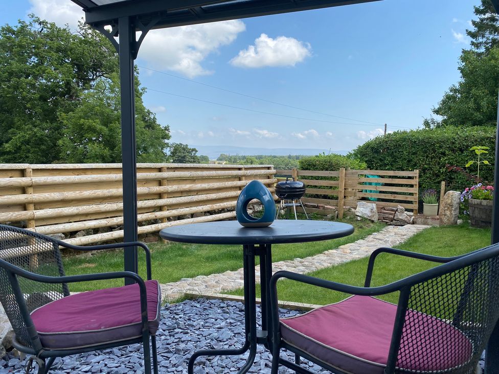 A garden with table and chairs, grill, and path at The Haven in Penrith