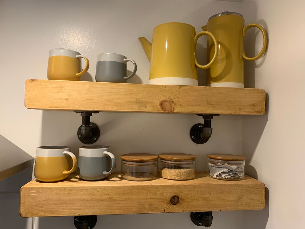 A kitchen shelf with mugs and storage jars at The Haven in Penrith