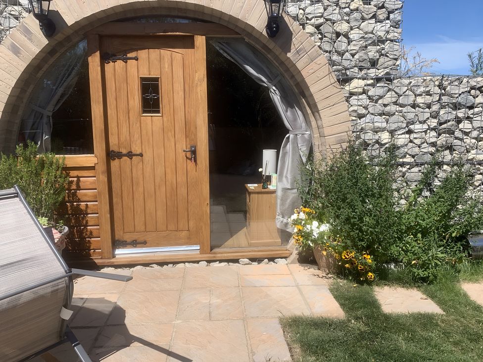 An entrance with a wooden door and flowers at Cosy Escape in Sheerness