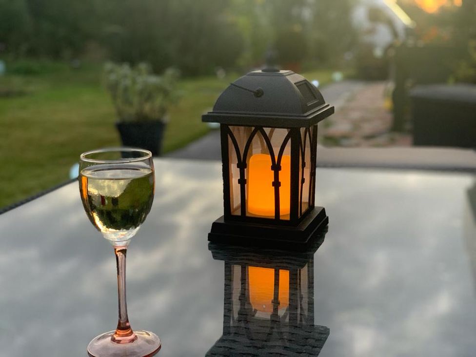 A glass of white wine and a lantern on a table at Cosy Escape in Sheerness