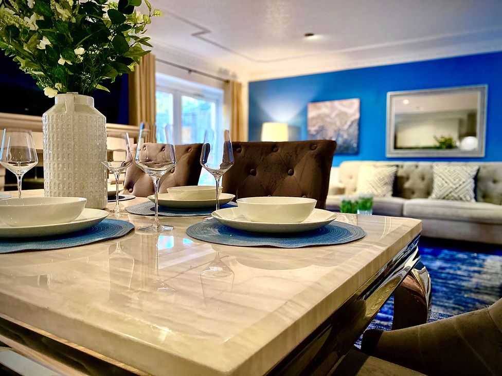 A dining table setup with plates and glasses in a living room at Anchor Hot Tub Suite in Lytham St. Annes