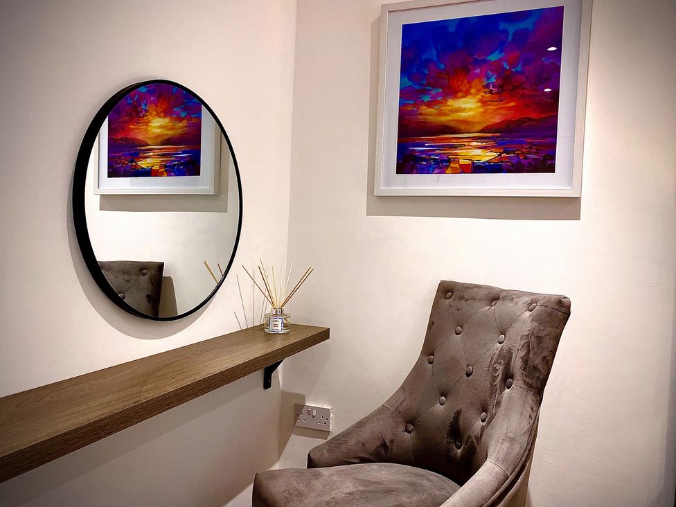 A chair and a shelf with a mirror and artwork at Anchor Hot Tub Suite in Lytham St. Annes