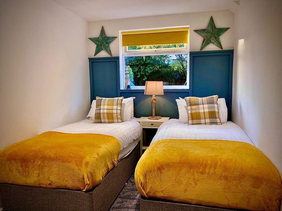 A bedroom with two beds and a lamp on a nightstand at Anchor Hot Tub Suite in Lytham St. Annes