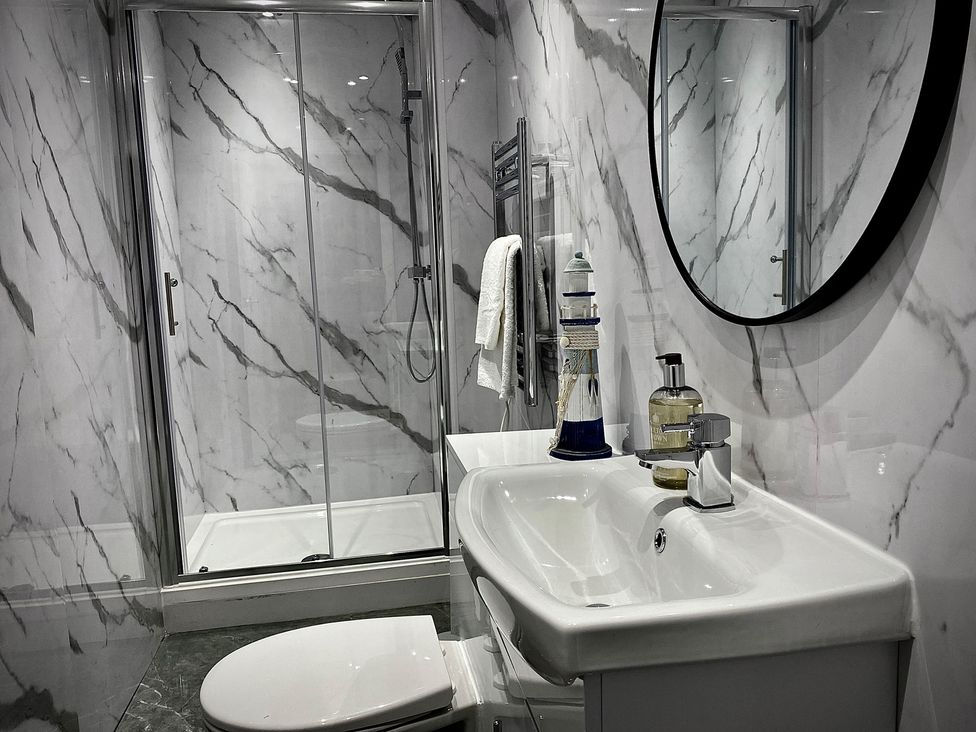 A bathroom with sink, toilet, shower and mirror at Anchor Hot Tub Suite Lytham St. Annes