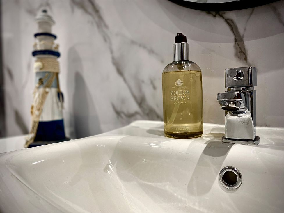 A sink with a soap dispenser and a lighthouse decoration at Anchor Hot Tub Suite in Lytham St. Annes