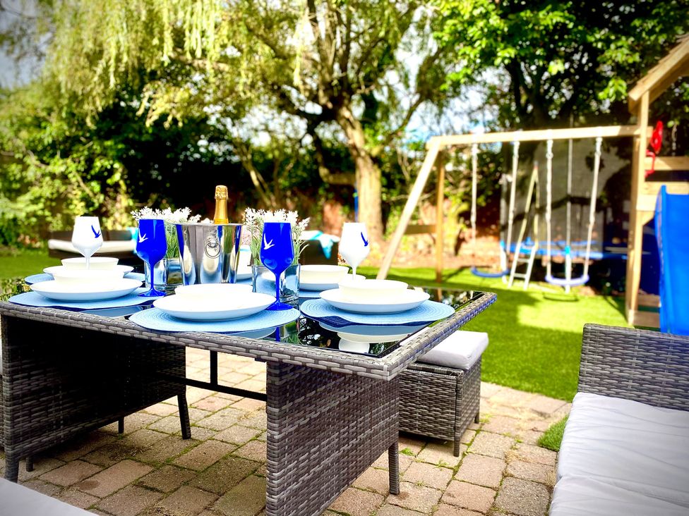 A dining table with plates and drinks set up in the garden at Anchor Hot Tub Suite Lytham St. Annes
