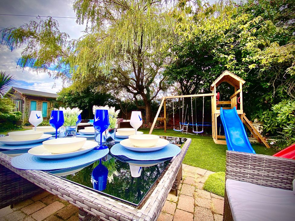 A garden with a table set and a slide at Anchor Hot Tub Suite in Lytham St. Annes
