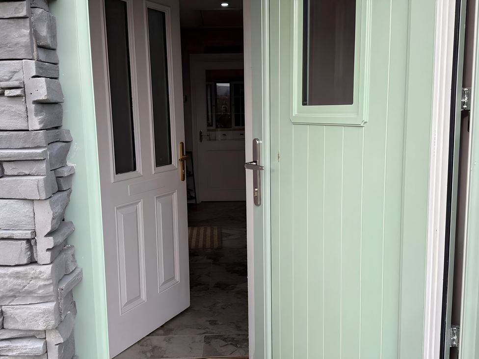An entryway with a mint green front door and an interior door at Cherry Chirp Cottage Enniskillen