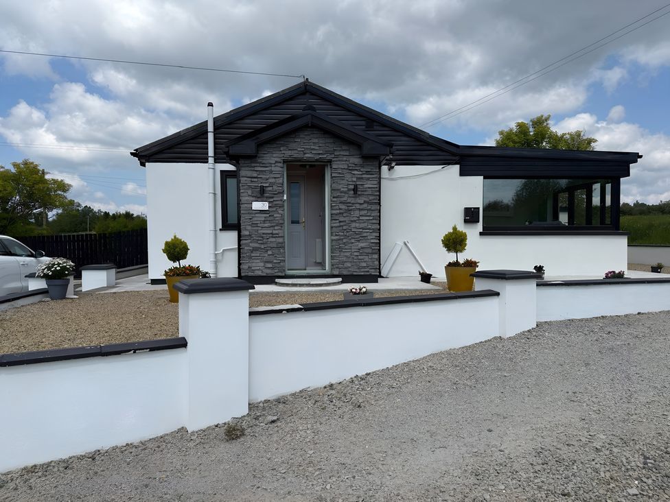 A house with a stone facade and garden features at Cherry Chirp Cottage Enniskillen