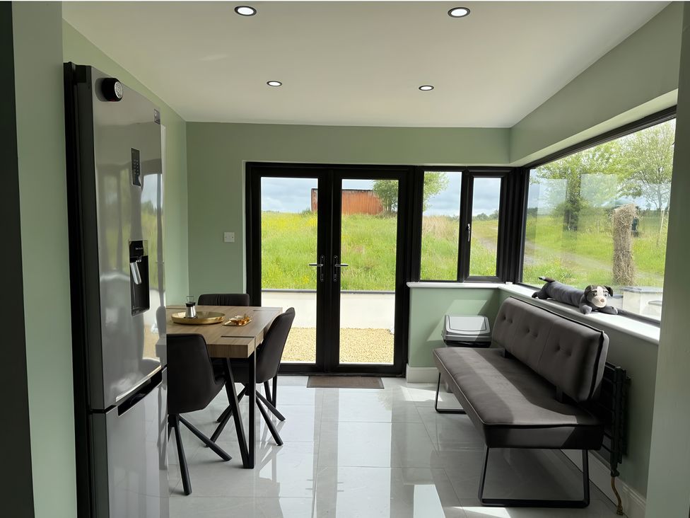 A kitchen with a table and chairs and a refrigerator at Cherry Chirp Cottage in Enniskillen