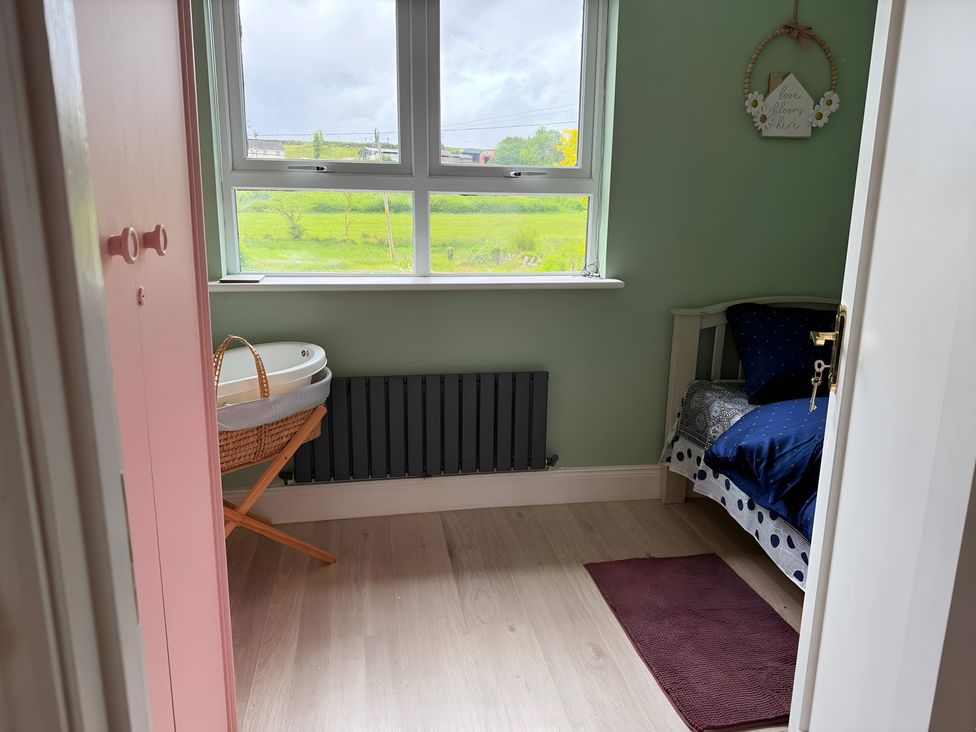 A bedroom with a bed, basket and window at Cherry Chirp Cottage Enniskillen