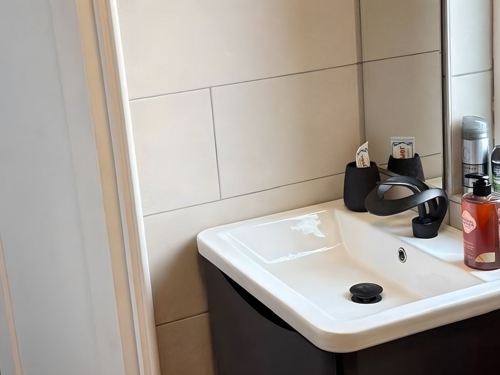 A bathroom with a sink and toiletries at Cherry Chirp Cottage in Enniskillen
