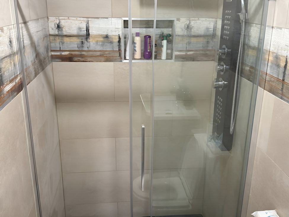A shower with a toilet and shelf in a bathroom at Cherry Chirp Cottage, Enniskillen