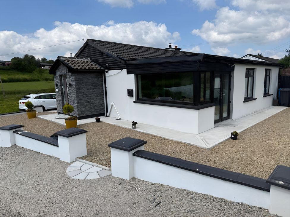 An exterior view of a house with gravel area and planters at Cherry Chirp Cottage Enniskillen