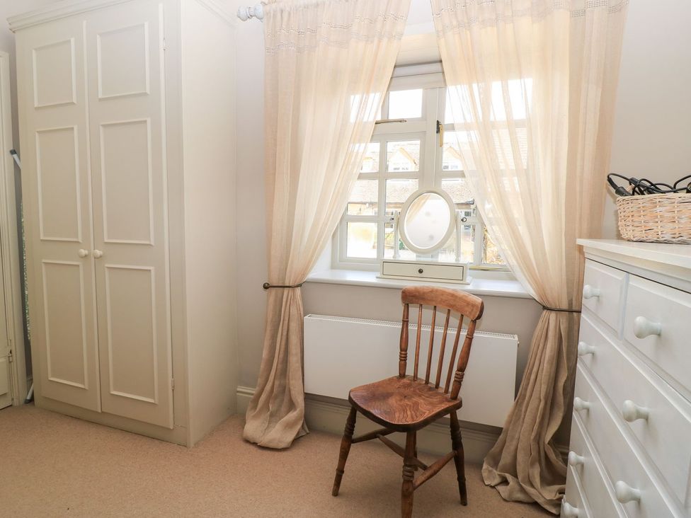A bedroom with a wardrobe, chair and window at Foxhill Farm Barn Cheltenham