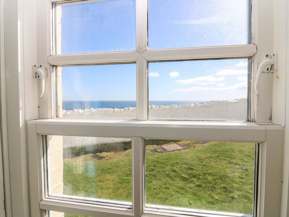 A view from a window showing ocean and grass at The Lighthouse Retreat in St Abbs
