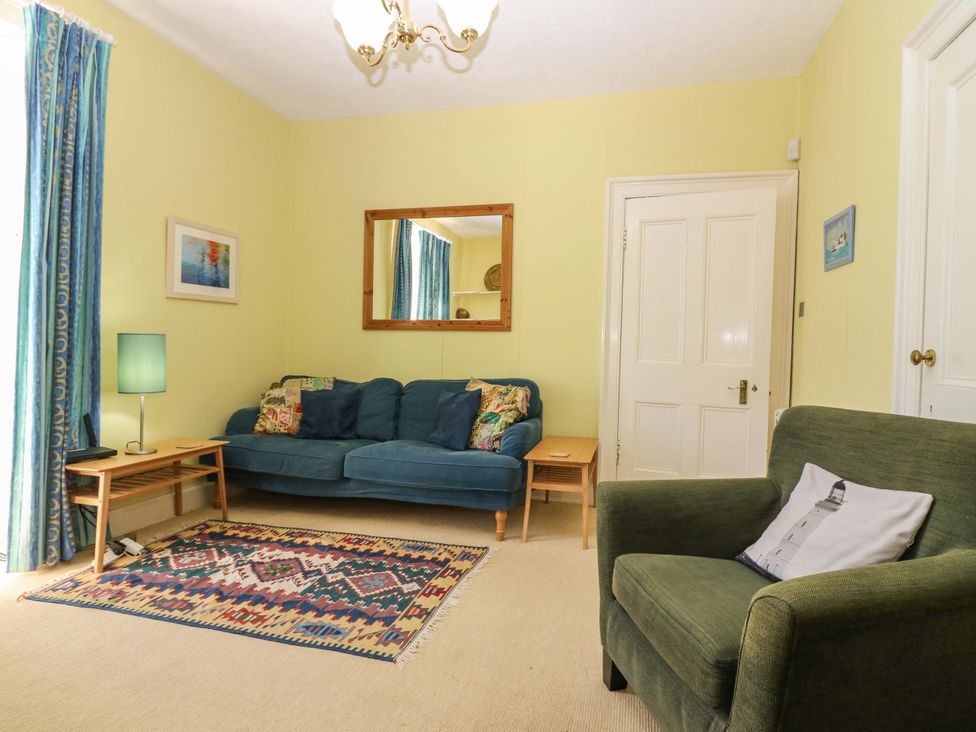 A living room with a sofa, table, and lamp at The Lighthouse Retreat in St Abbs
