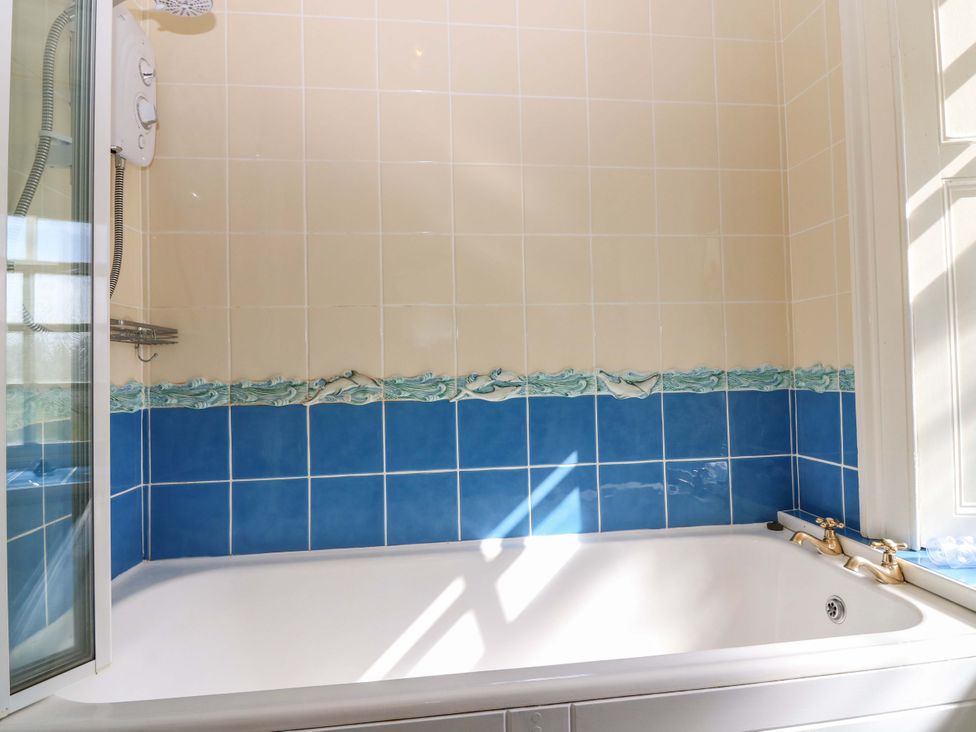 A bathroom with a bathtub and shower at The Lighthouse Retreat, St Abbs