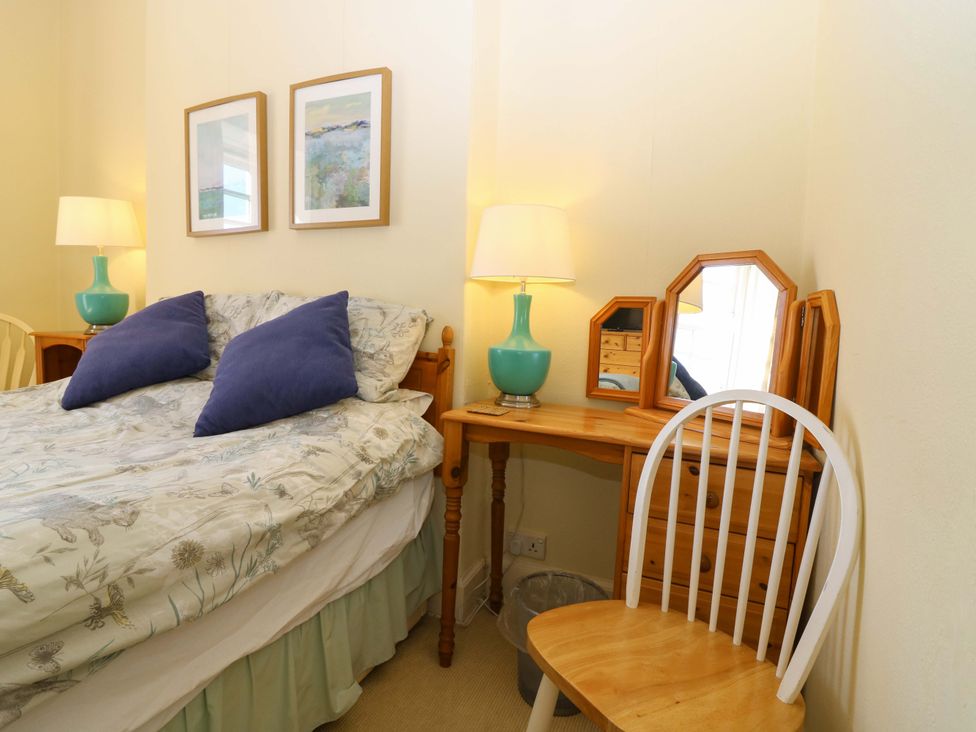 A bedroom with a bed and a table with a lamp and mirror at The Lighthouse Retreat in St Abbs