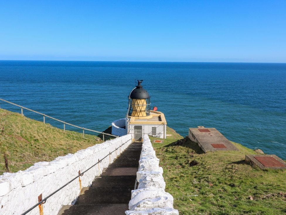 A lighthouse on a cliffside overlooking the ocean at The Lighthouse Retreat in St Abbs