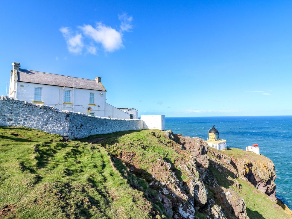 A house and lighthouse on a cliff overlooking the ocean at The Lighthouse Retreat St Abbs