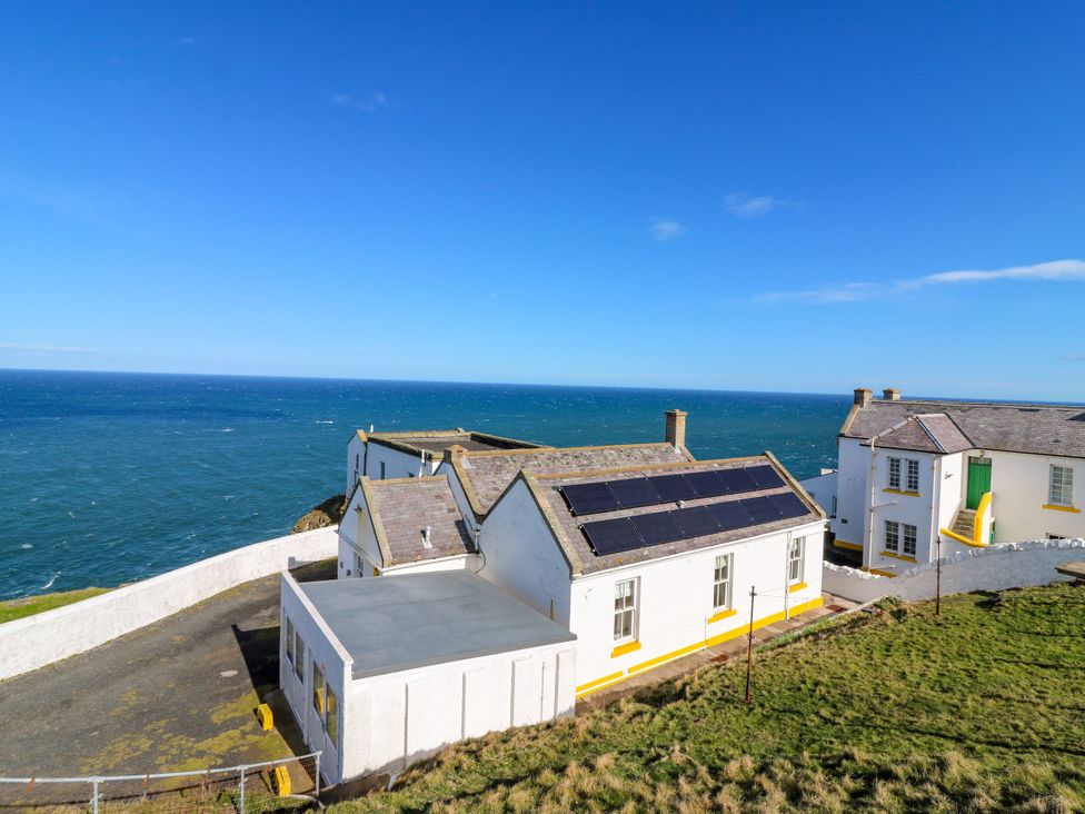 An exterior view of a house with solar panels overlooking the ocean at The Lighthouse Retreat in St Abbs