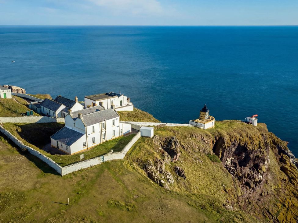 A coastal view with a lighthouse and buildings near the sea at Keepers Fold at The Lighthouse St Abbs