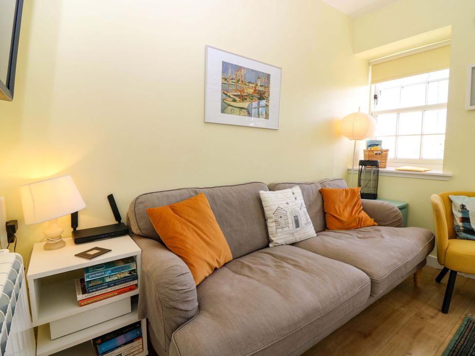 A living room with a sofa and books on shelves at Keepers Fold at The Lighthouse St Abbs