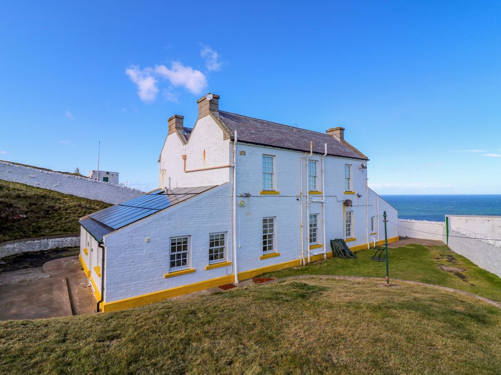 An outdoor view of a building with grass and sea at Keepers Fold at The Lighthouse St Abbs