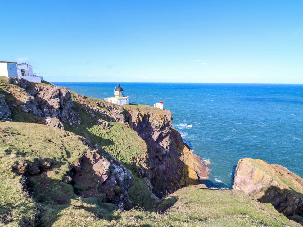 A coastal scene with a lighthouse on a cliff at Keepers Fold at The Lighthouse St Abbs