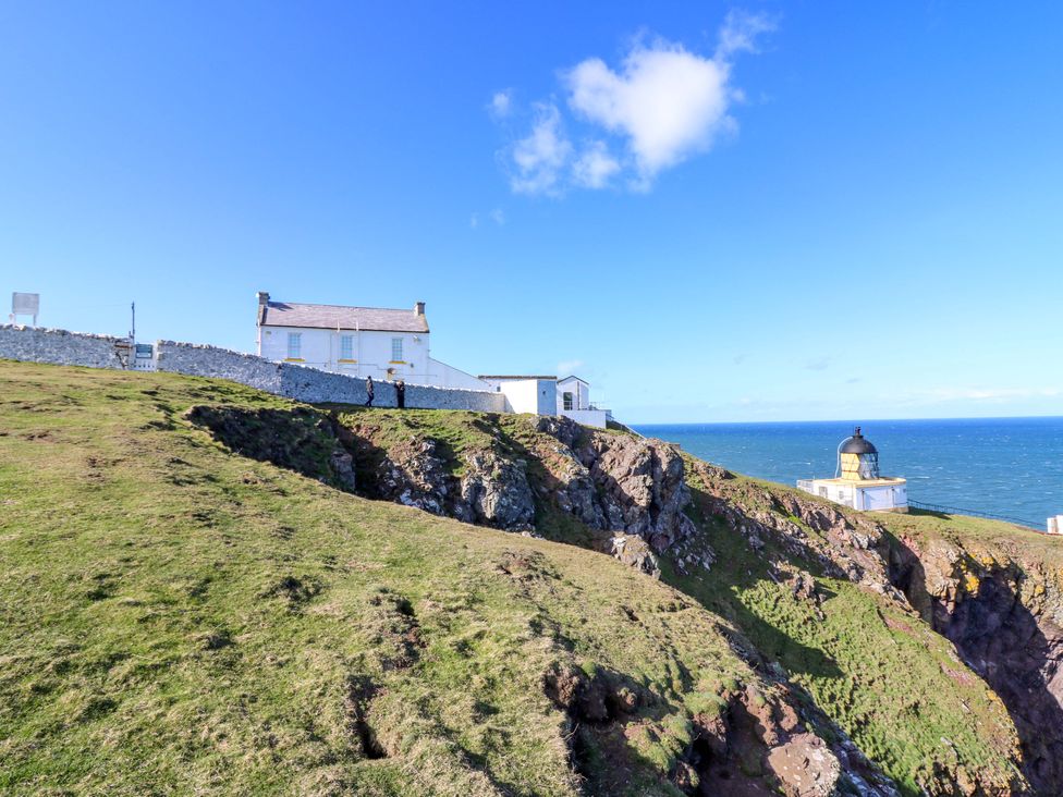 A lighthouse and house on a cliff overlooking the ocean at Keepers Fold at The Lighthouse St Abbs
