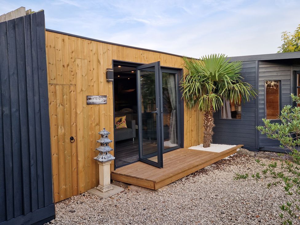 An exterior view of a wooden cabin entrance at Birdsong lodge near Hawthorn Farm near Sutton-On-Sea