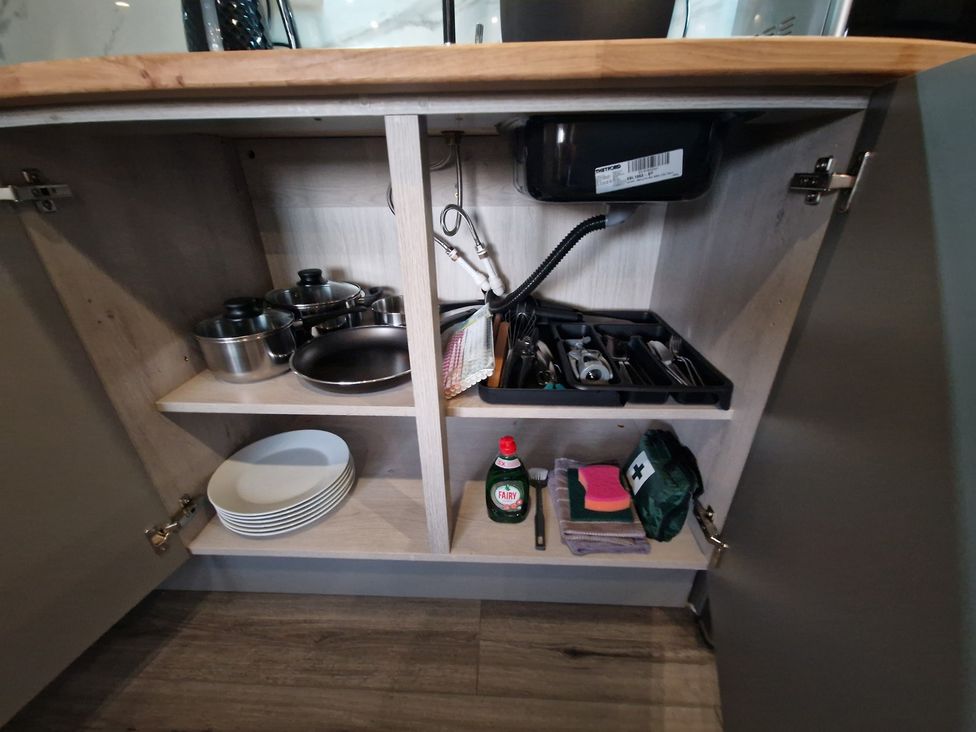 A kitchen cabinet with pots, plates, and utensils at Birdsong lodge near Hawthorn Farm