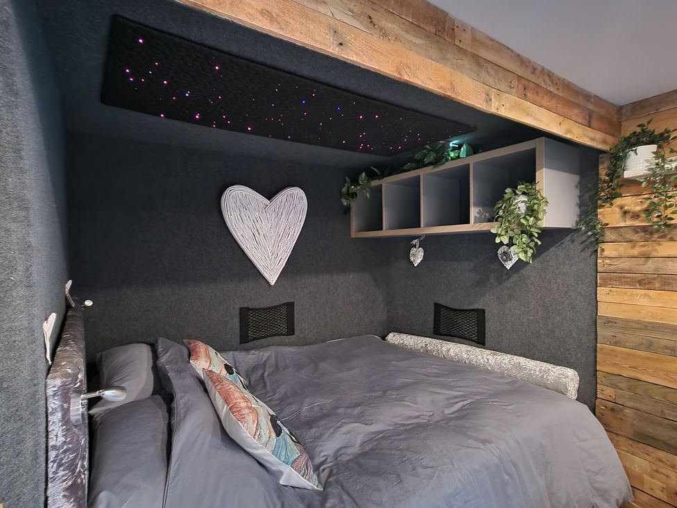 A bedroom with a bed and shelf at Birdsong lodge near Sutton-On-Sea