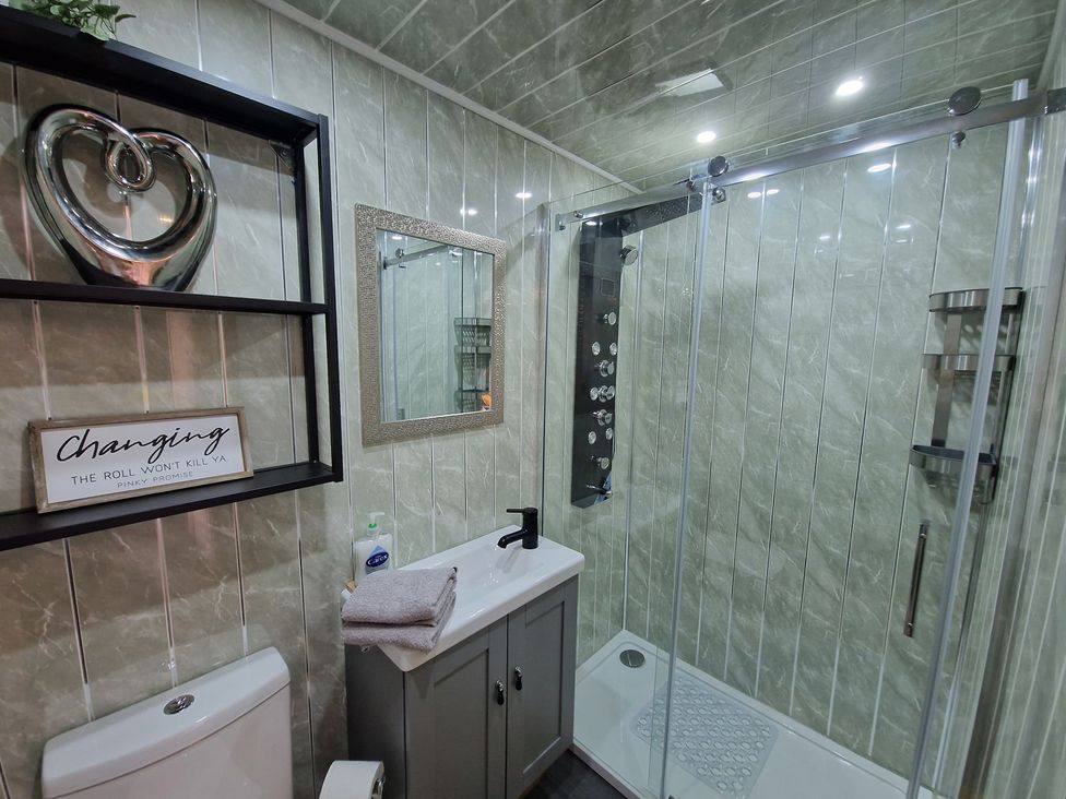 A bathroom with a shower, toilet, and sink at Birdsong lodge, Hawthorn Farm near Sutton-On-Sea