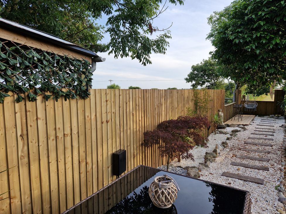 A garden with a wooden fence and gravel path at Birdsong lodge near Hawthorn Farm near Sutton-On-Sea