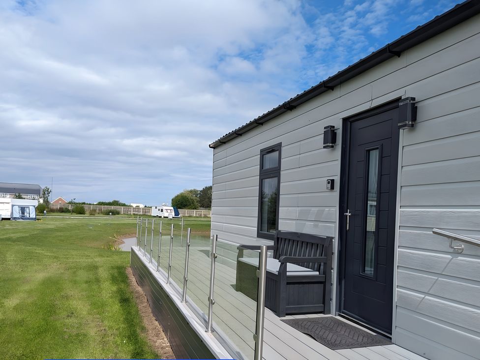 A house with a bench and railing at Waterside Lodge in Mablethorpe
