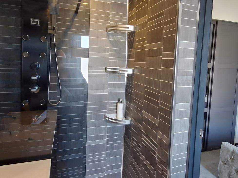 A shower area with a wall panel and shelves at Waterside Lodge in Mablethorpe