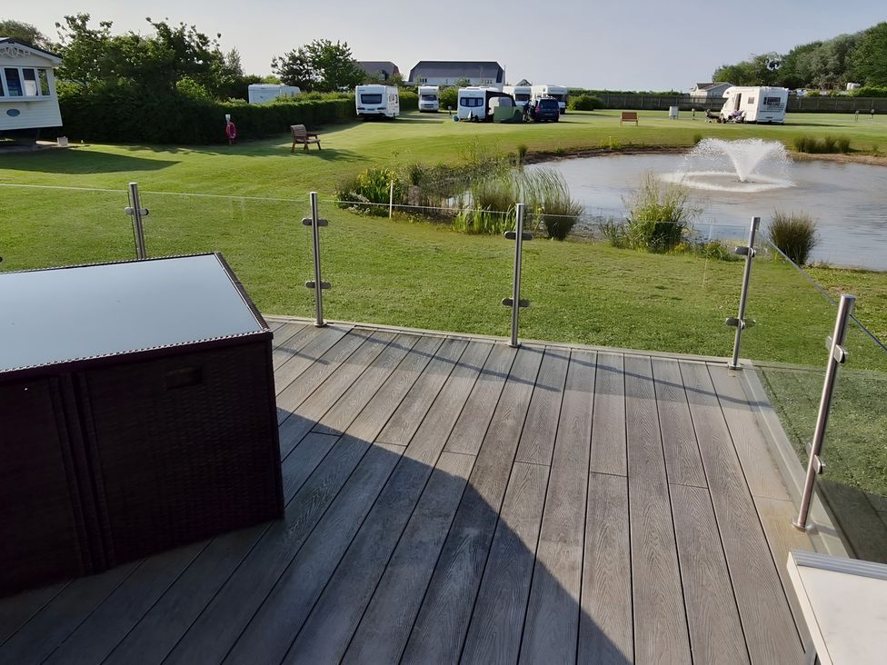 An outdoor area with a pond and caravans at Waterside Lodge in Mablethorpe