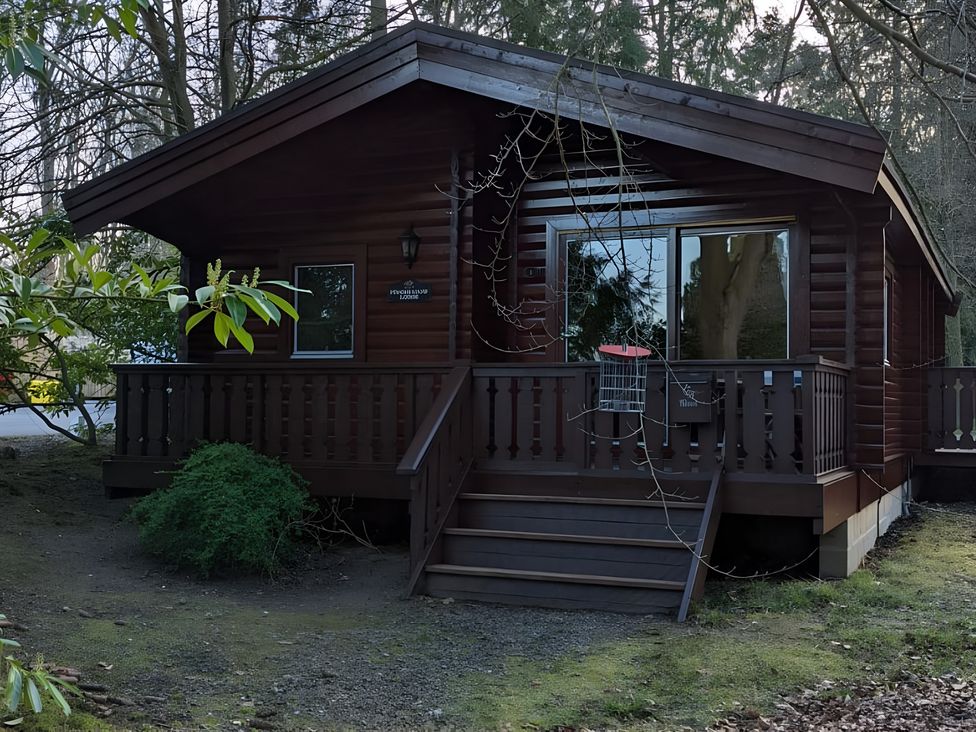 A log cabin with a deck and stairs at Pineshadow Lodge in Louth