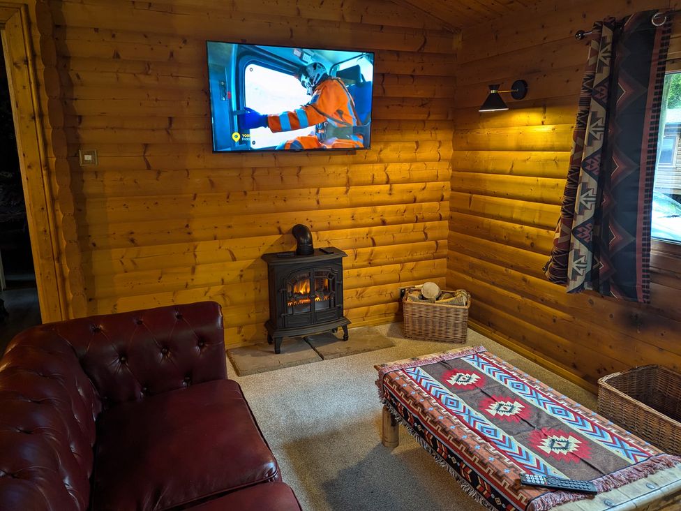 A living room with a wood stove and television at Pineshadow Lodge in Louth