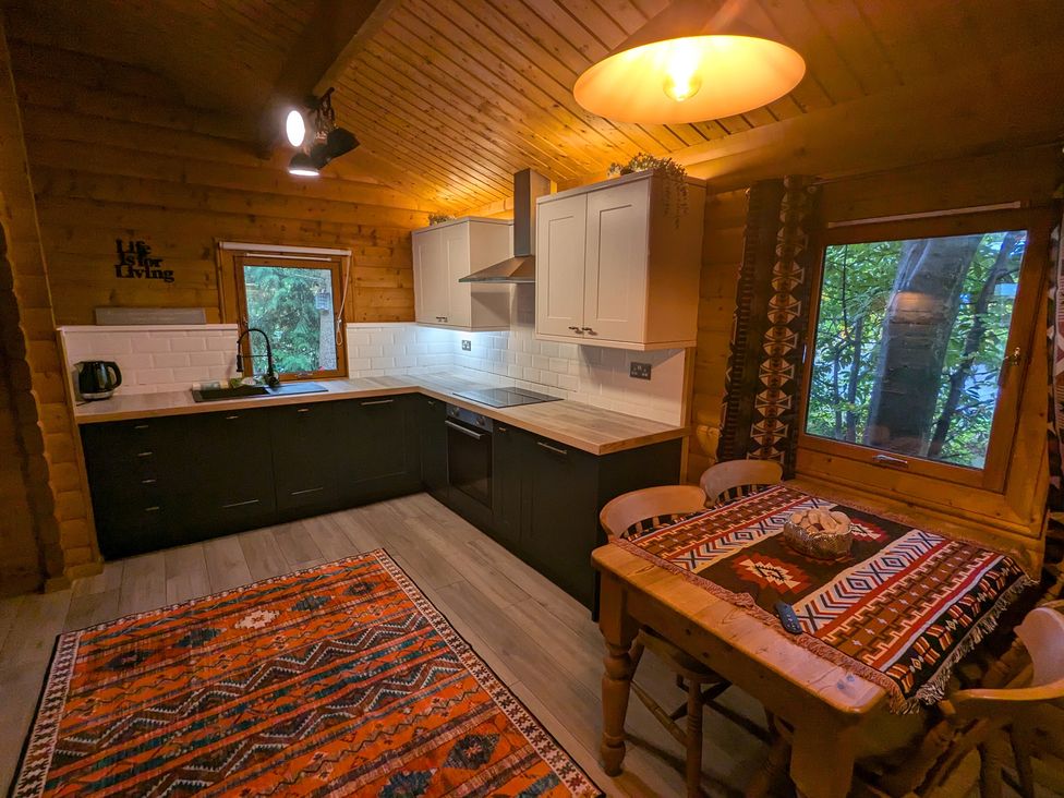 A kitchen with cabinets and a dining table at Pineshadow Lodge in Louth