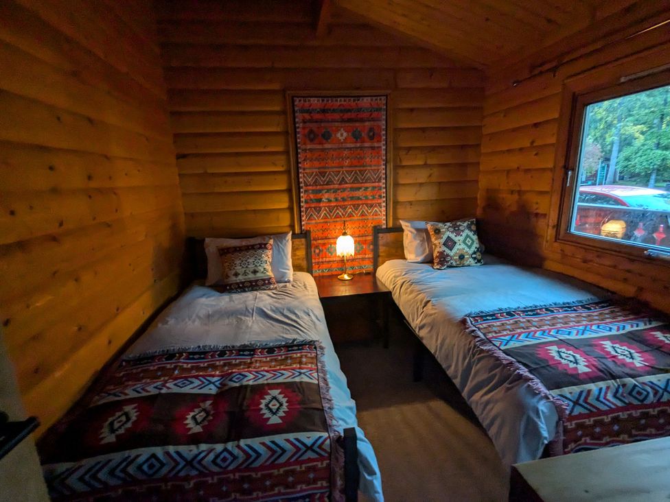A bedroom with two beds and a lamp at Pineshadow Lodge in Louth