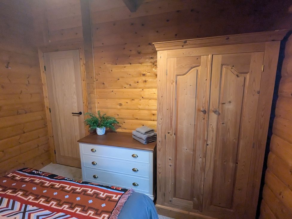 A bedroom with a wooden wardrobe and dresser at Pineshadow Lodge in Louth