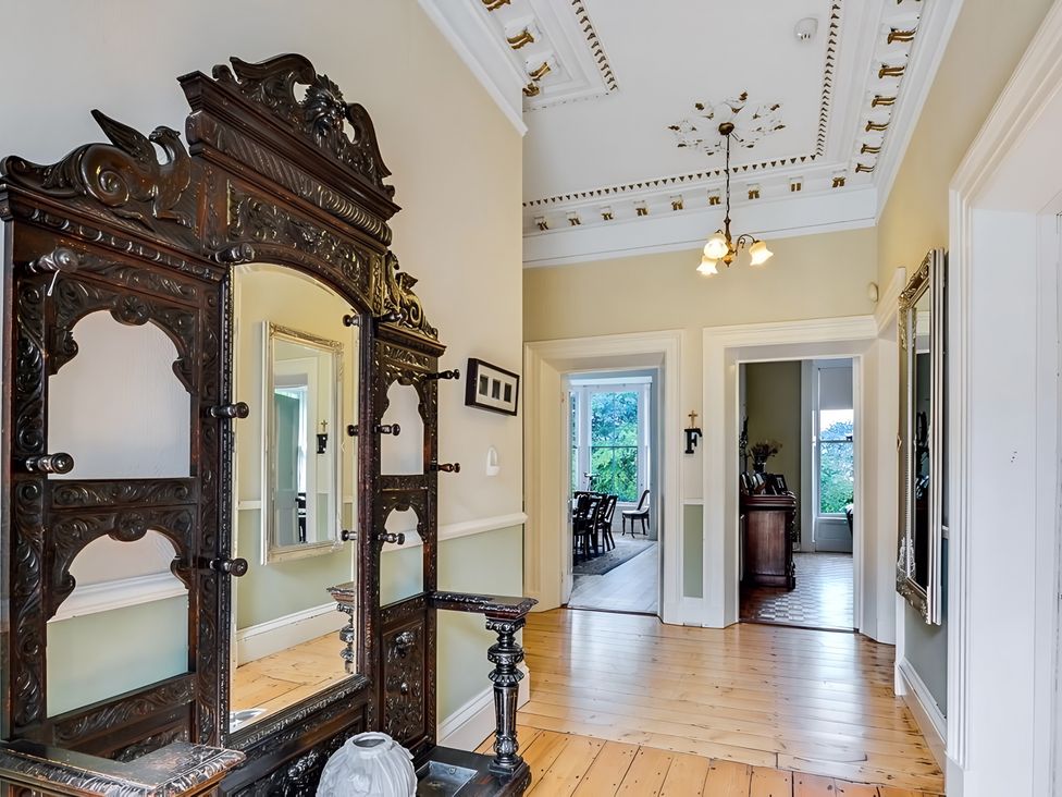 A hallway with an ornate cabinet and mirror at Fountain Hill House in Londonderry