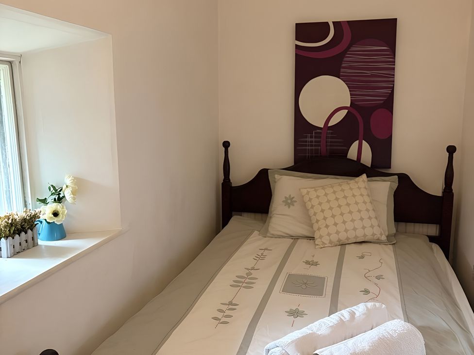 A bedroom with a bed, pillows, flowers and wall decor at Fountain Hill House Londonderry