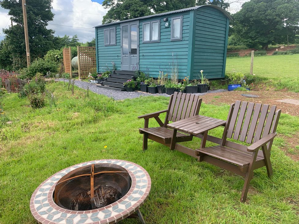 An outdoor area with a shepherd's hut and chairs at Bluebell Shepherd’s Hut in Llanfairpwllgwyngyll