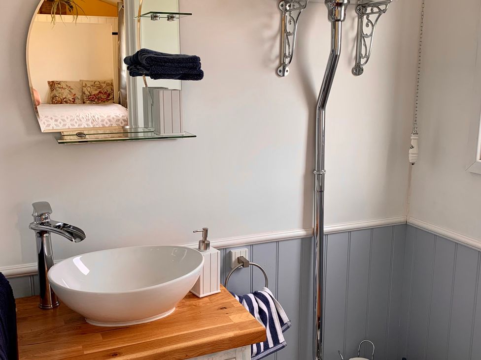 A bathroom with a sink and mirror at Bluebell Shepherd’s Hut in Llanfairpwllgwyngyll