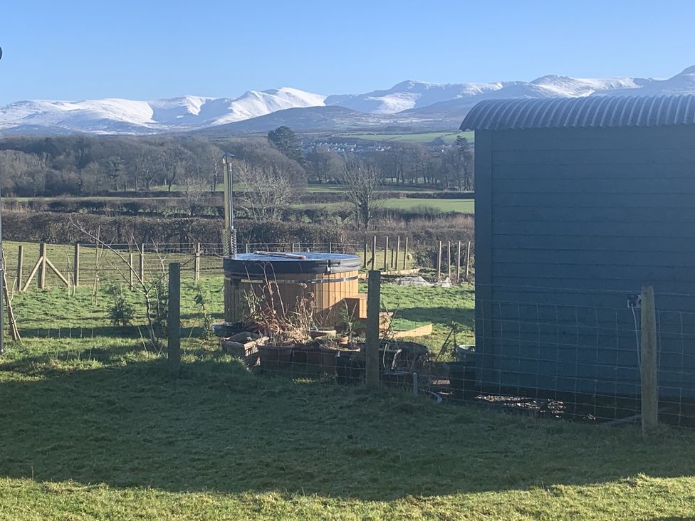 An outdoor area with a hot tub and shed at Bluebell Shepherd’s Hut in Llanfairpwllgwyngyll