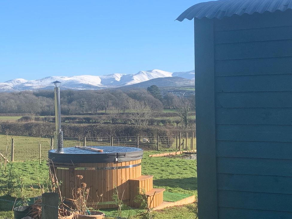 An outdoor view featuring a hot tub and mountains at Bluebell Shepherd’s Hut in Llanfairpwllgwyngyll